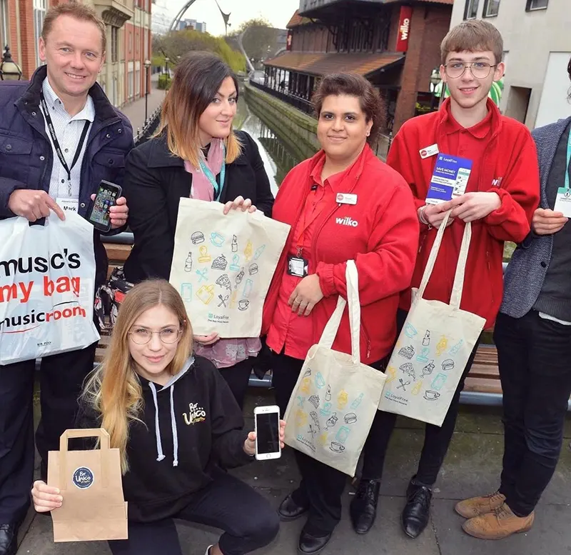LoyalFree customers holding branded tote bags